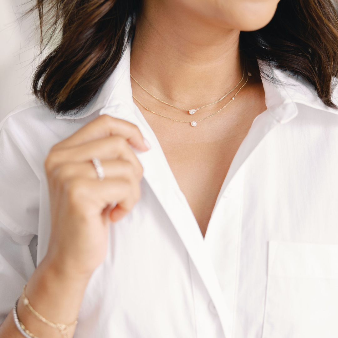 Woman wearing layered gold necklaces with small diamond pendants, exemplifying the elegance of delicate layering necklaces.