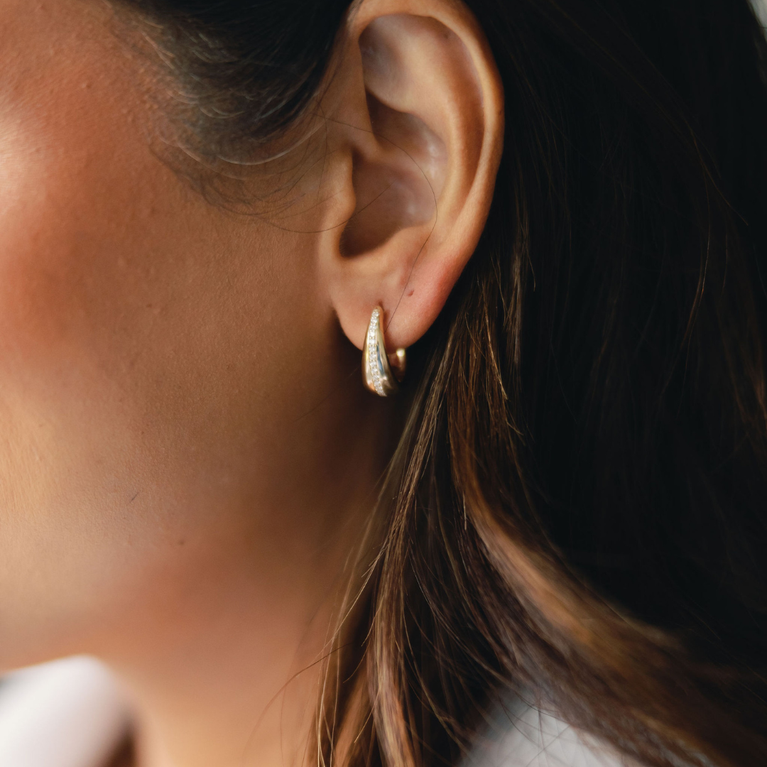 Close-up of a woman's ear wearing a pair of minimalistic hoop earrings, emphasizing the elegant and simple design of the jewelry.