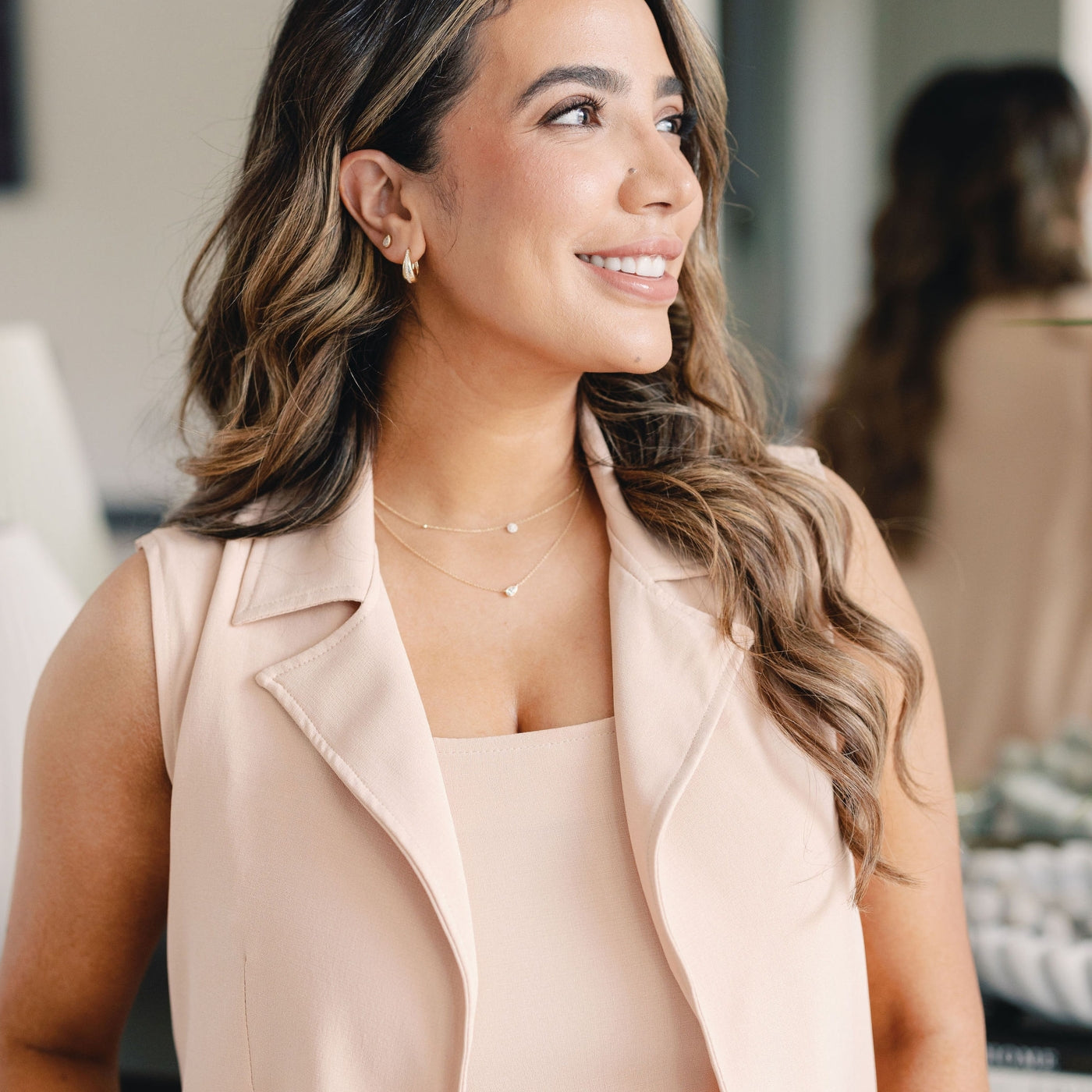 Seema of Seema Jewelry & Co smiling and wearing the PEAR-FECT Solitaire Necklace, featuring a 0.30 CT lab-grown diamond pendant on a 14K gold chain, along with other layered necklaces.