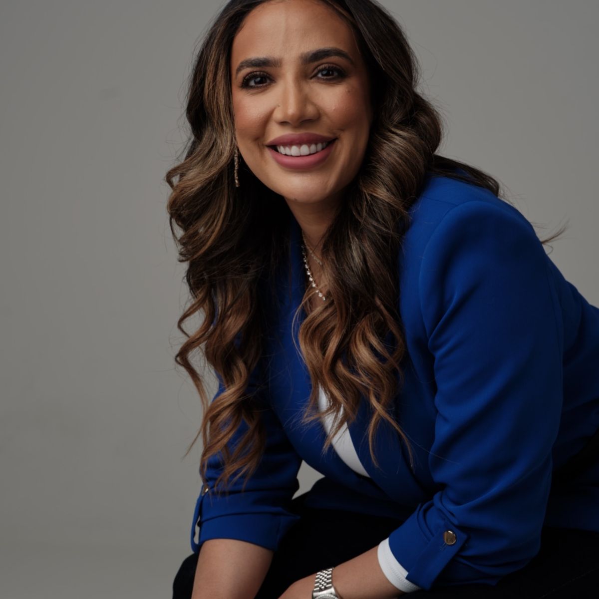 Portrait of Seema Patel showcasing her bespoke jewelry designs in a blue blazer.