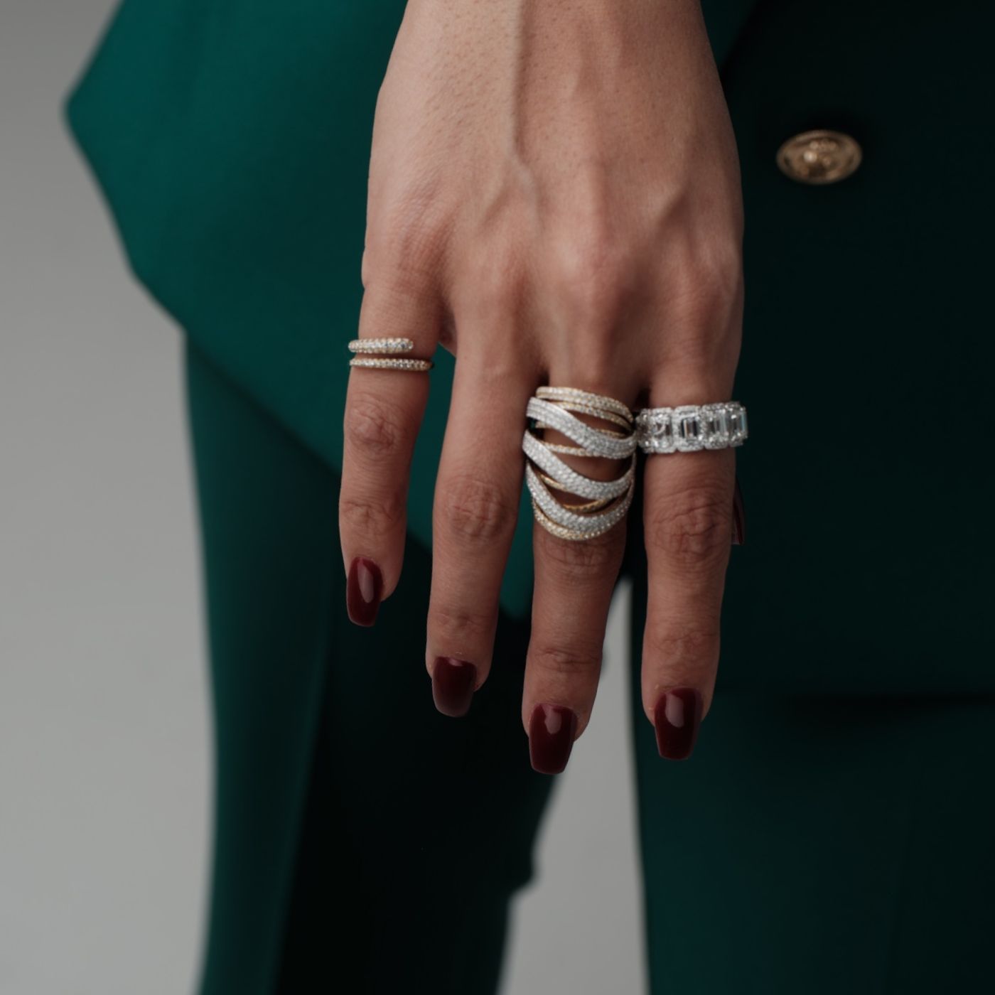 Close-up of a hand wearing diamond-studded wedding bands and statement rings by Seema Jewelry and Co.